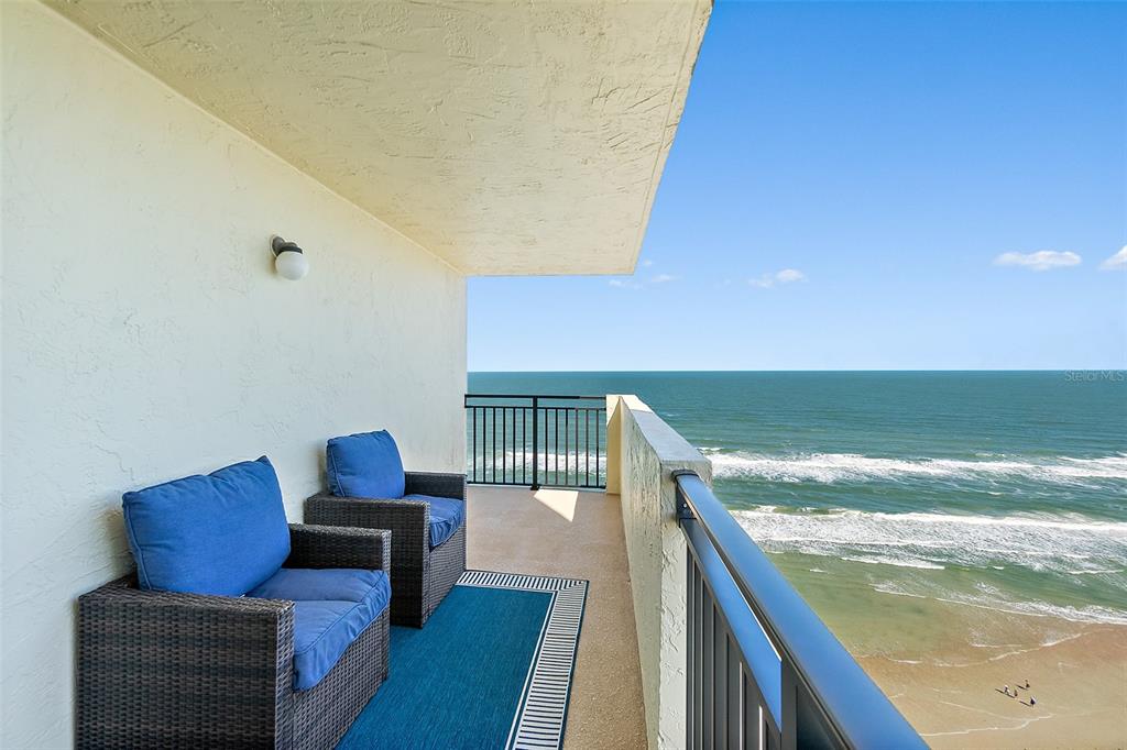 A balcony with two wicker chairs overlooks the ocean and a sandy beach — 2947 S ATLANTIC AVENUE UNIT 1903, DAYTONA BEACH, FL