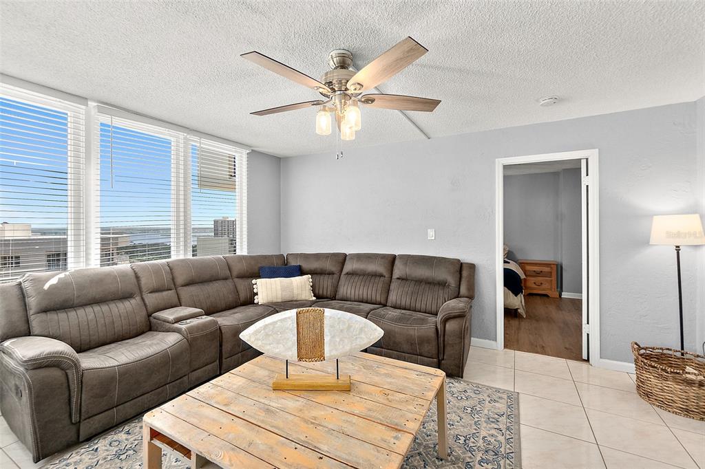 A living room features a large brown sectional sofa, a wooden coffee table, and tile flooring — 2947 S ATLANTIC AVENUE UNIT 1903, DAYTONA BEACH, FL