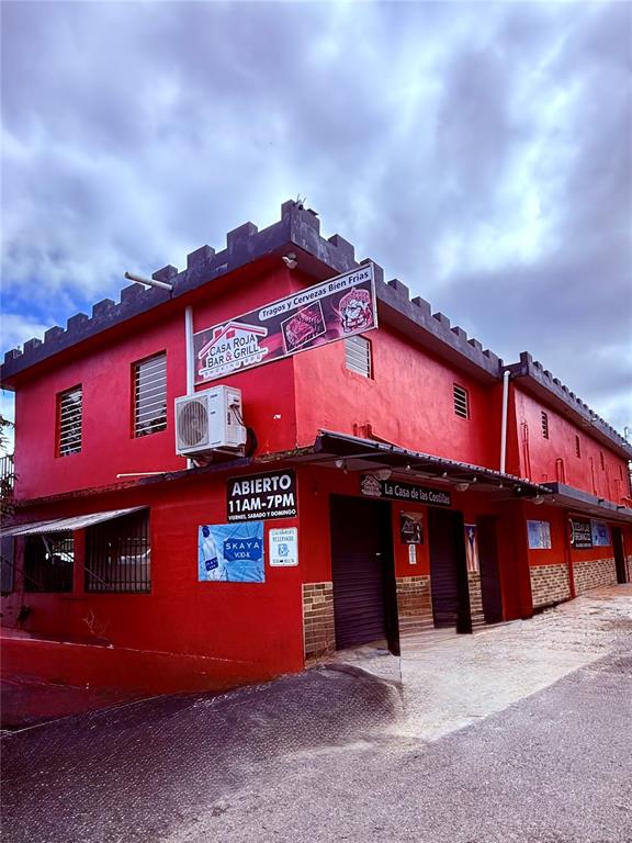 A red two-story commercial building with a crenelated roofline and a corner sign — 149 ROUTE UNIT KM 18.3, CIALES, PR