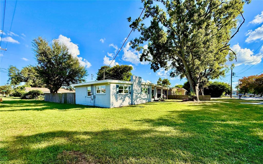 A single-story house with a light-colored exterior sits on a large, grassy lot — 1604 CRYSTAL COURT E, LAKELAND, FL