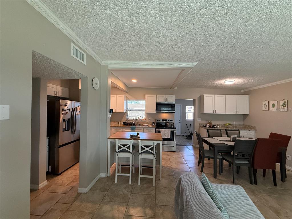 A kitchen and dining area with white cabinets, stainless steel appliances, and tile flooring — 1604 CRYSTAL COURT E, LAKELAND, FL