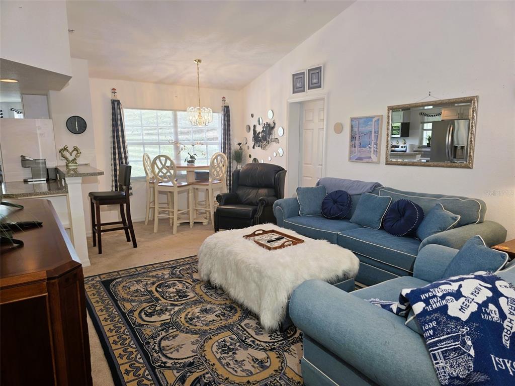 A living room features a blue sectional sofa, a white faux fur ottoman, and dining area — 2077 WETLAND POINT UNIT 1301, LUTZ, FL