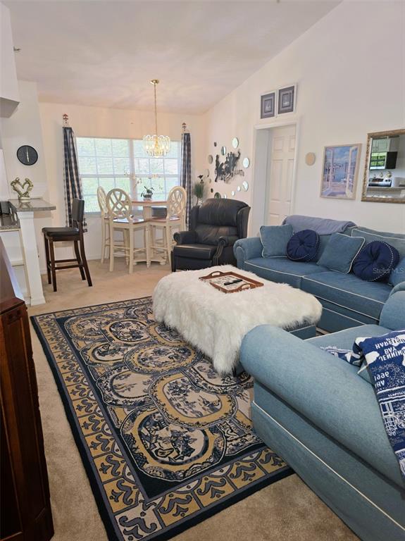 A living room with blue sofas, a white faux fur ottoman, and a dining area — 2077 WETLAND POINT UNIT 1301, LUTZ, FL
