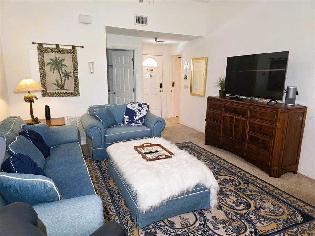 A living room features blue furniture, a white faux-fur ottoman, and a wooden media console — 2077 WETLAND POINT UNIT 1301, LUTZ, FL