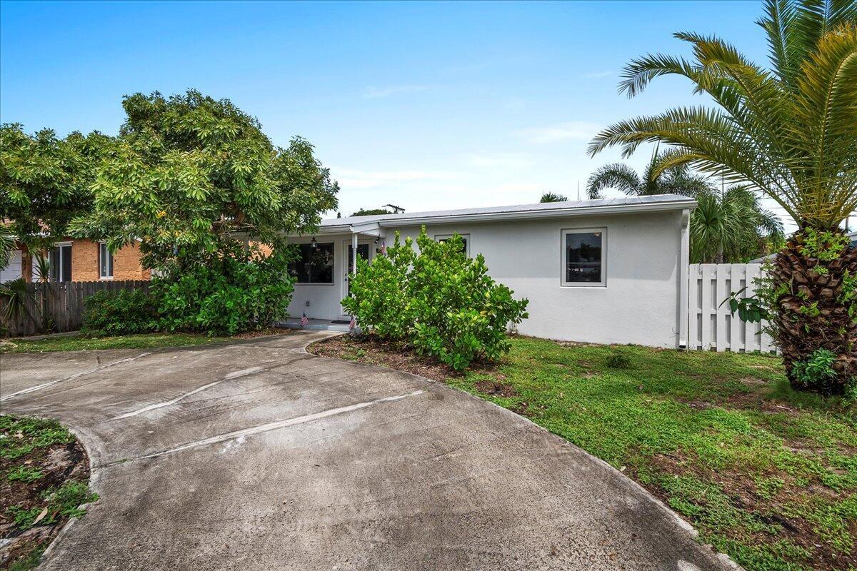 A single-story house with a concrete driveway, green landscaping, and a palm tree — 727 Bunker Road, West Palm Beach FL 33405, WEST PALM BEACH, FL