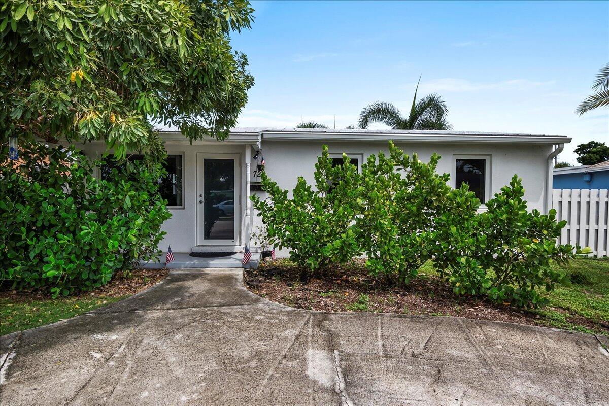 A single-story house with a white exterior, a concrete driveway, and lush green landscaping — 727 Bunker Road, West Palm Beach FL 33405, WEST PALM BEACH, FL