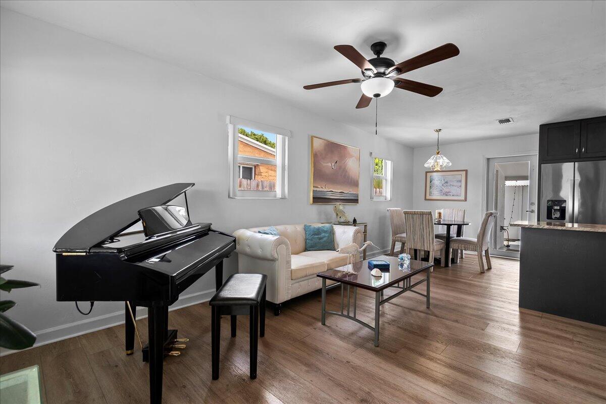 A living and dining area features a grand piano, white sofa, and wood-look flooring — 727 Bunker Road, West Palm Beach FL 33405, WEST PALM BEACH, FL