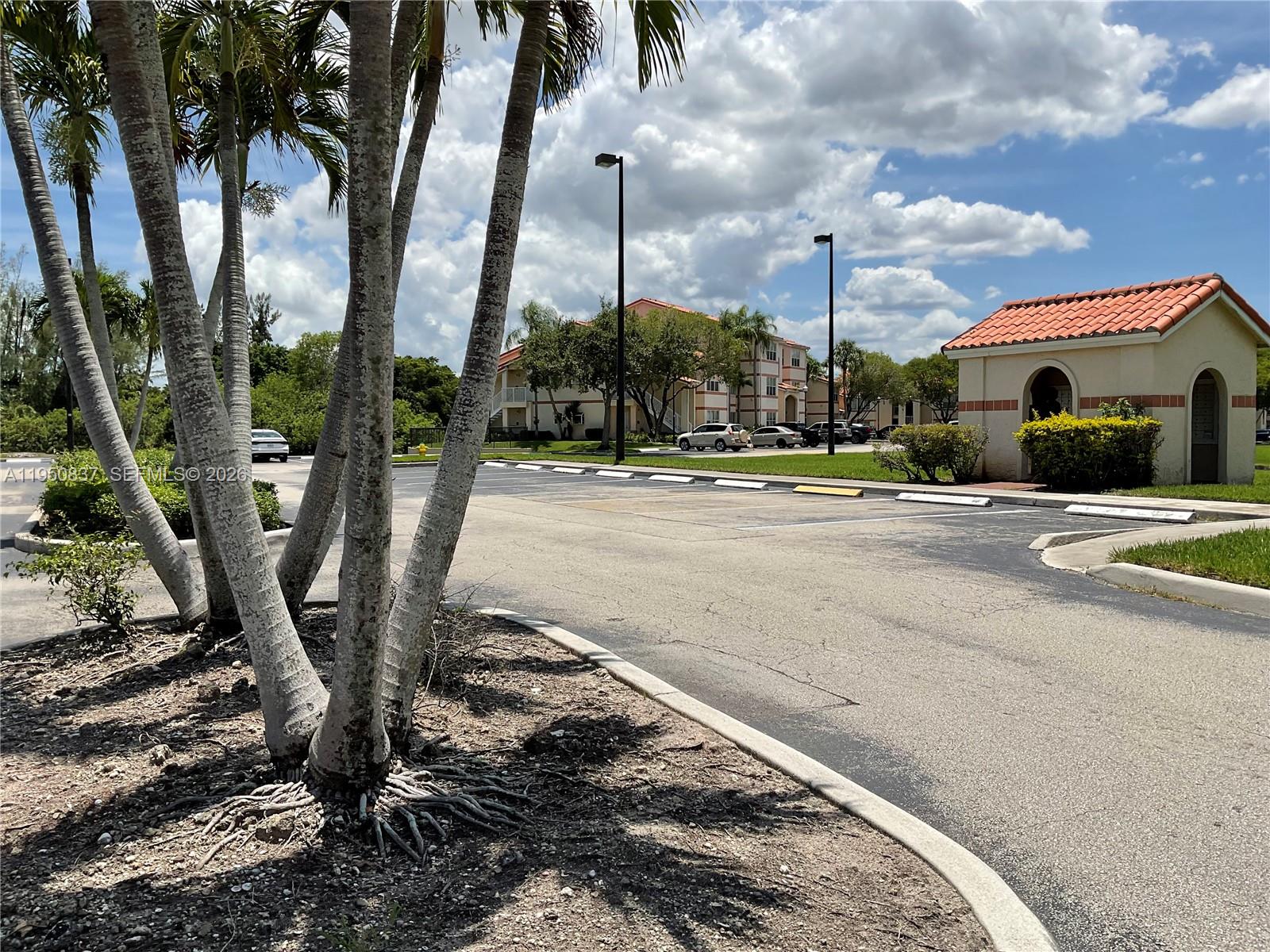 A parking lot with palm trees in the foreground and apartment buildings in the background — 3320 N Pinewalk Dr N # 1715, Margate FL 33063, MARGATE, FL