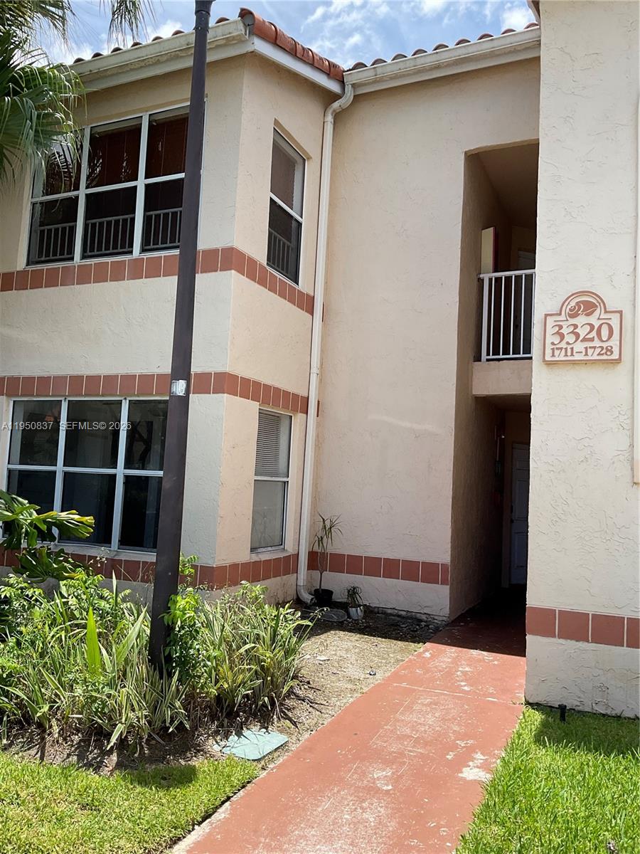 The exterior of a two-story stucco apartment building features a red walkway and unit signage — 3320 N Pinewalk Dr N # 1715, Margate FL 33063, MARGATE, FL