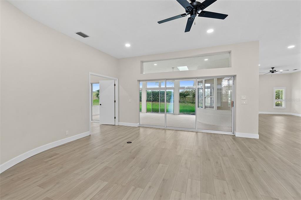 A spacious living room features light wood-look flooring, a ceiling fan, and large sliding glass doors — 38 KINGSLEY CIRCLE, ORMOND BEACH, FL