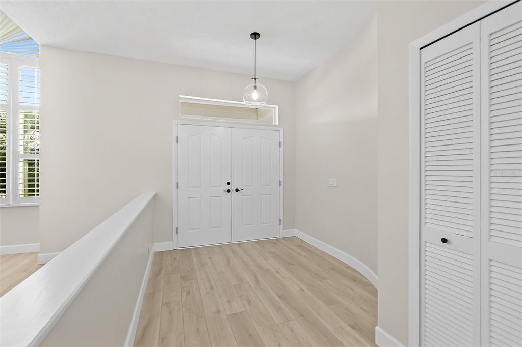 A bright entryway features light wood-look flooring, white double doors, and a modern pendant light — 38 KINGSLEY CIRCLE, ORMOND BEACH, FL
