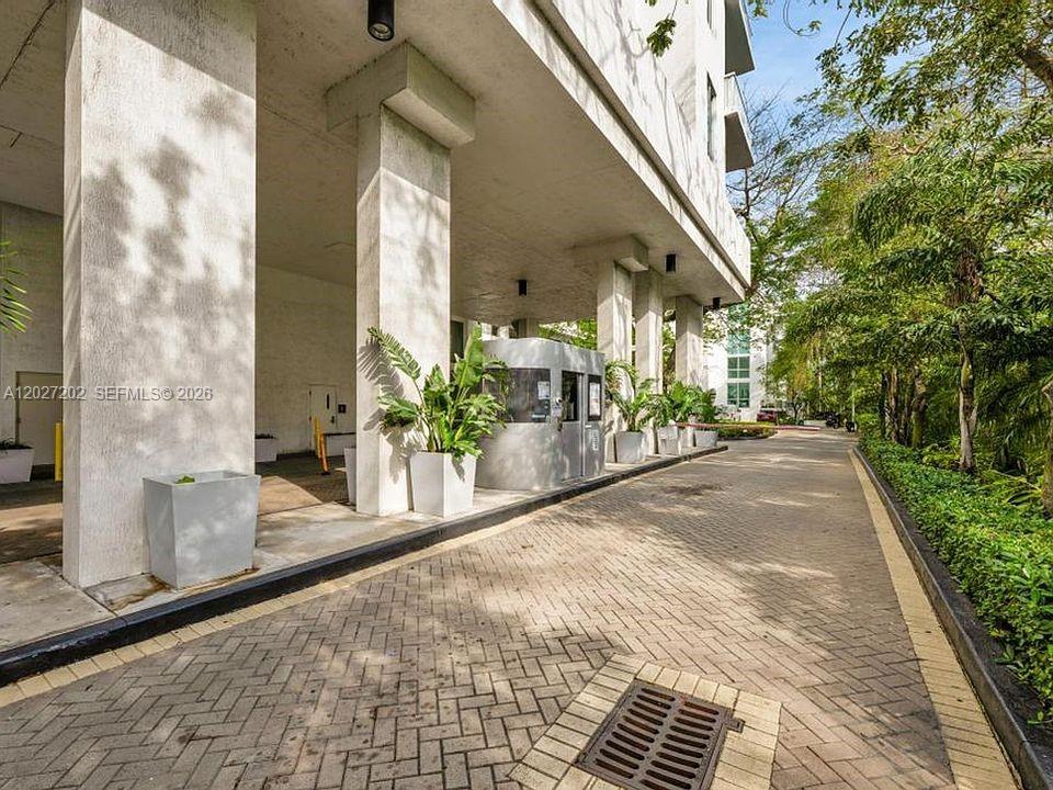 A paved driveway leads to a covered building entrance with concrete columns and a guardhouse — 1861 NW S River Dr # 2008, Miami FL 33125, MIAMI, FL
