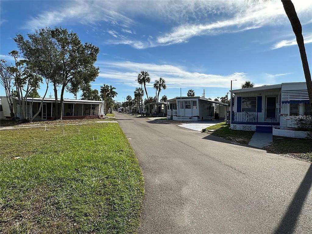 A paved street runs between manufactured homes under a blue sky with scattered clouds — 4851 W GANDY BOULEVARD UNIT B5L37, TAMPA, FL