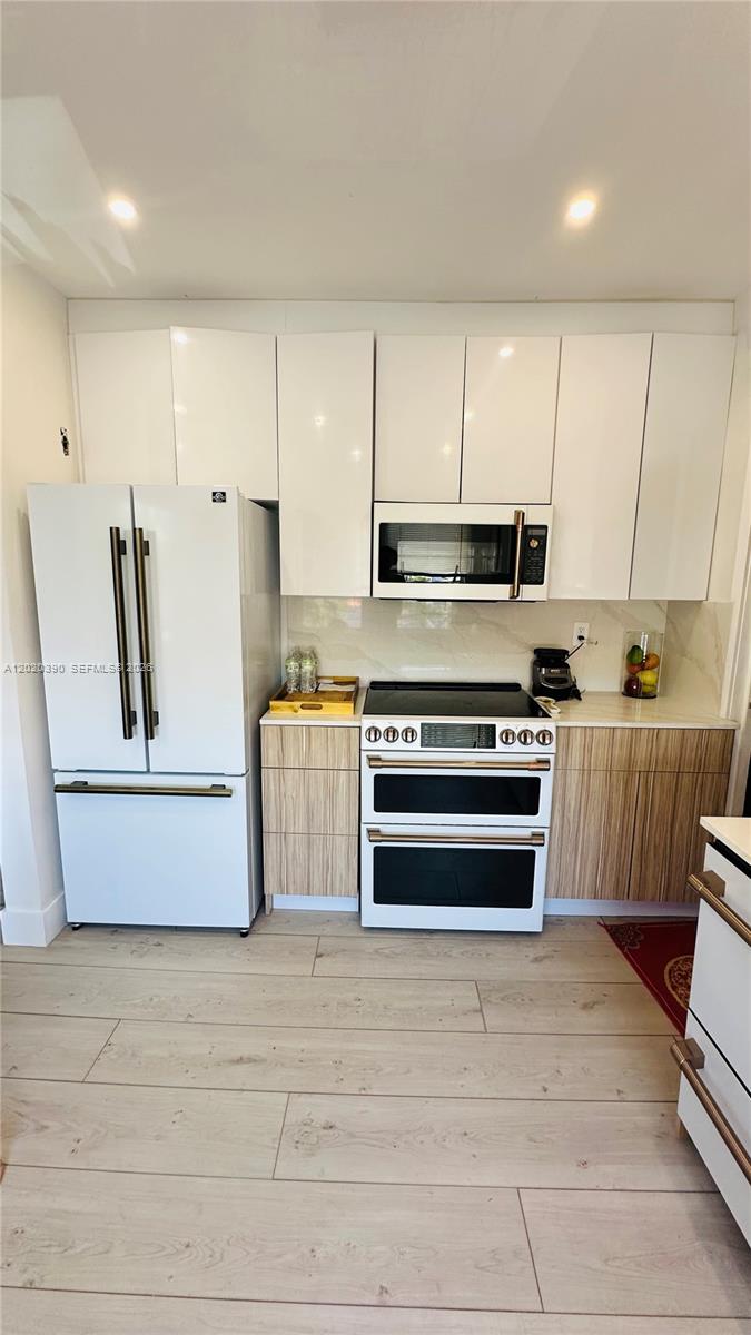 A kitchen features white upper cabinets, wood-grain lower cabinets, and white appliances with gold handles — 1670 SW 20th St # 2, Miami FL 33145, MIAMI, FL