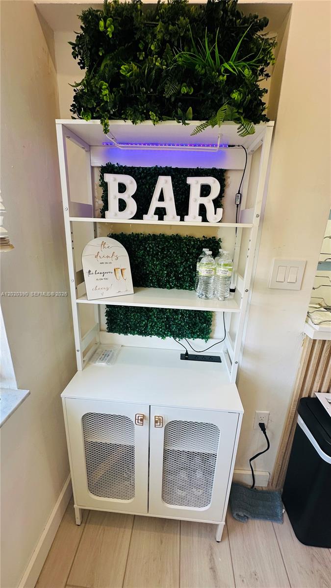A white shelving unit with a bar sign and greenery sits against a wall — 1670 SW 20th St # 2, Miami FL 33145, MIAMI, FL
