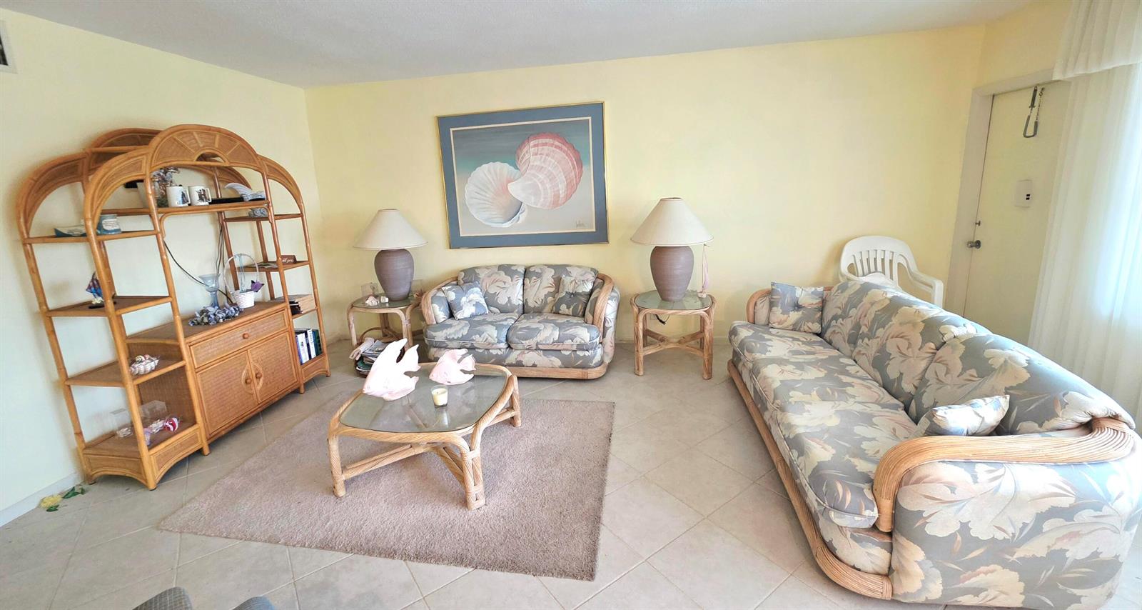 A living room features rattan furniture, floral upholstery, a glass coffee table, and tiled floors — 3200 NE 7th Court # 202b, Pompano Beach FL 33062, POMPANO BEACH, FL