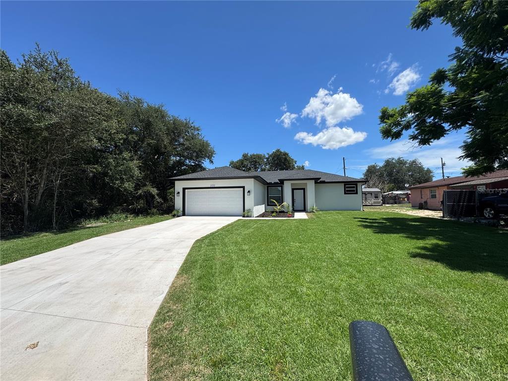 A single-story house with a white exterior, black trim, and a concrete driveway — 222 FLORIDA AVENUE, DUNDEE, FL