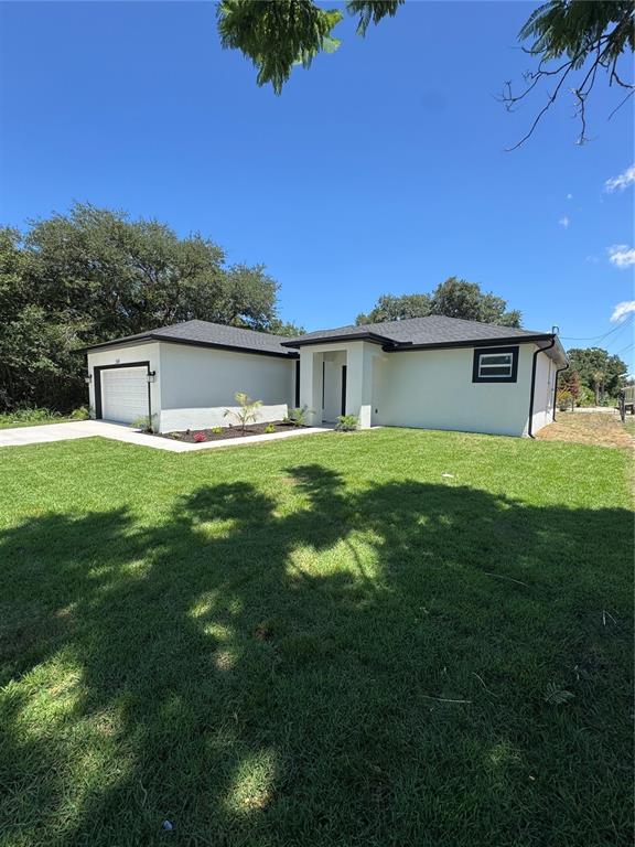 A single-story house with a white stucco exterior, dark roof, and an attached garage — 222 FLORIDA AVENUE, DUNDEE, FL