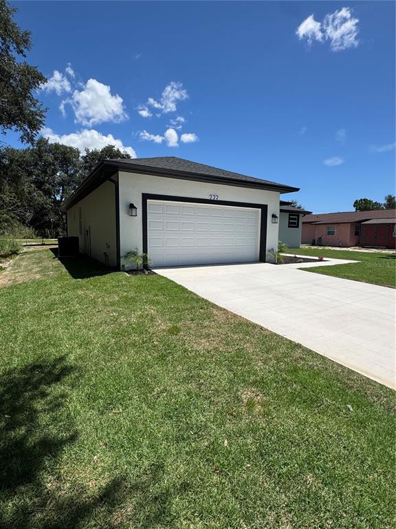 A white detached garage with a black trim and a concrete driveway under a blue sky — 222 FLORIDA AVENUE, DUNDEE, FL