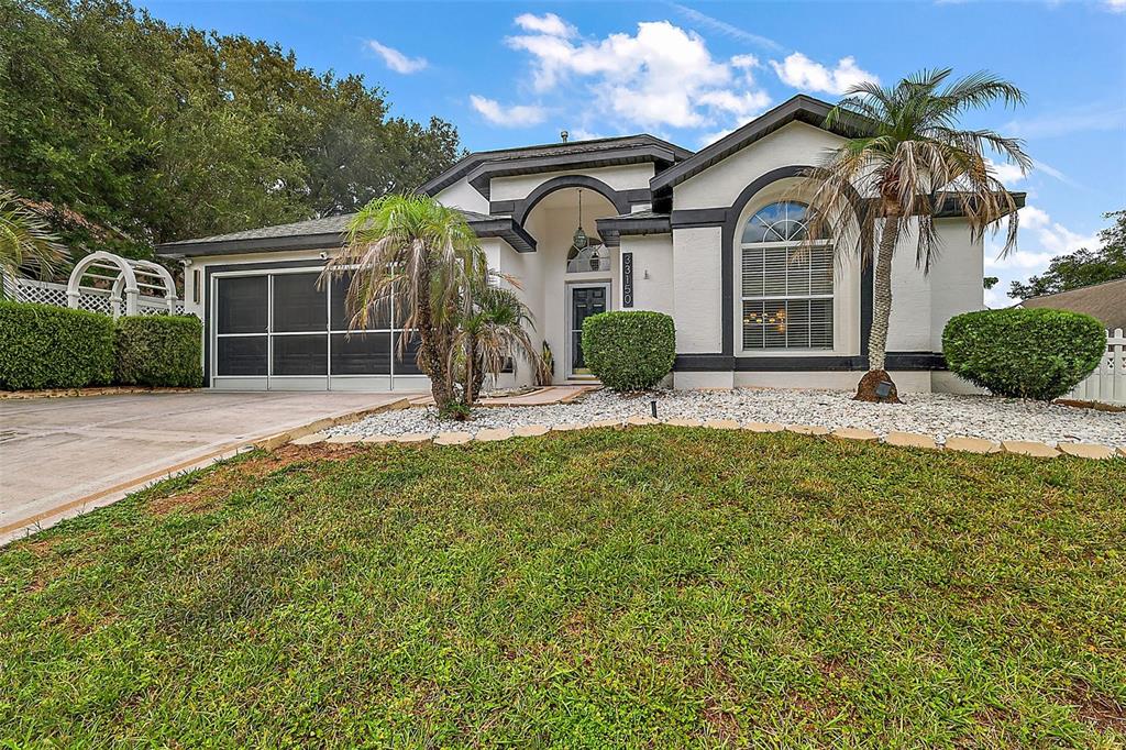 A single-story house with a white stucco exterior, dark trim, and a screened-in garage — 33150 KAYLEE WAY, LEESBURG, FL