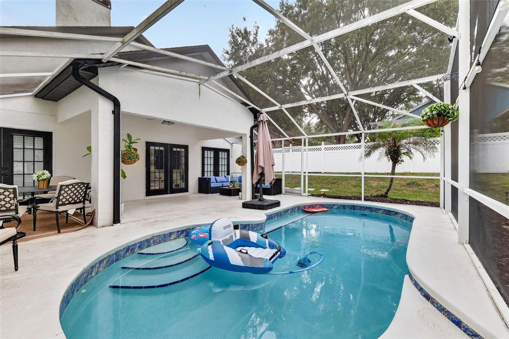 A screened-in patio features a swimming pool with built-in steps and outdoor furniture — 33150 KAYLEE WAY, LEESBURG, FL