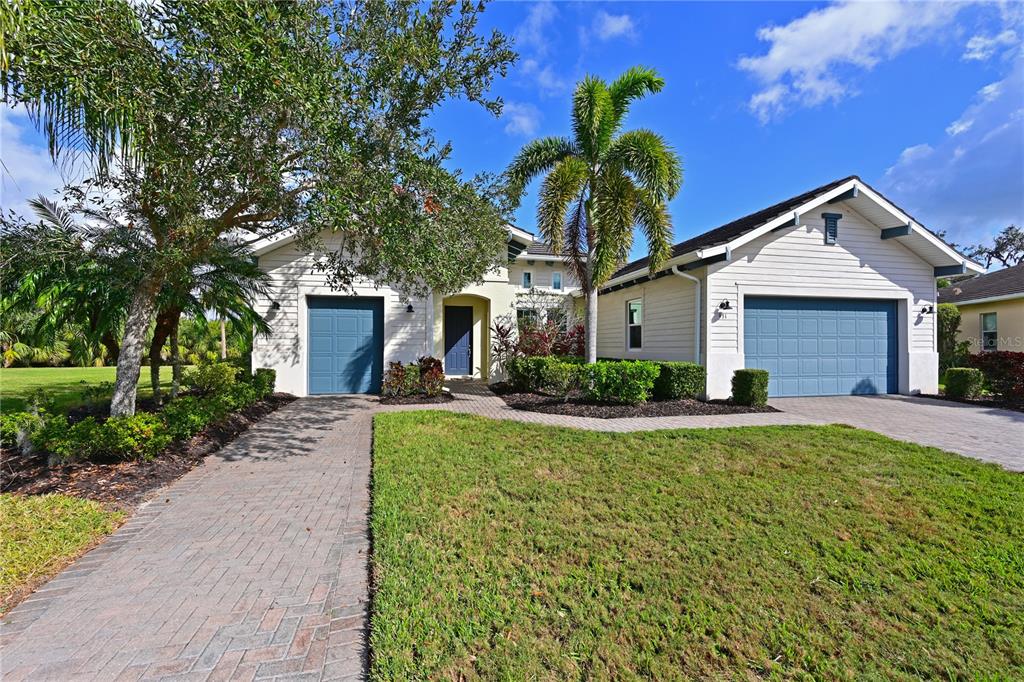 A single-story house with a blue garage, a paved walkway, and a palm tree — 931 MANGROVE EDGE COURT, BRADENTON, FL