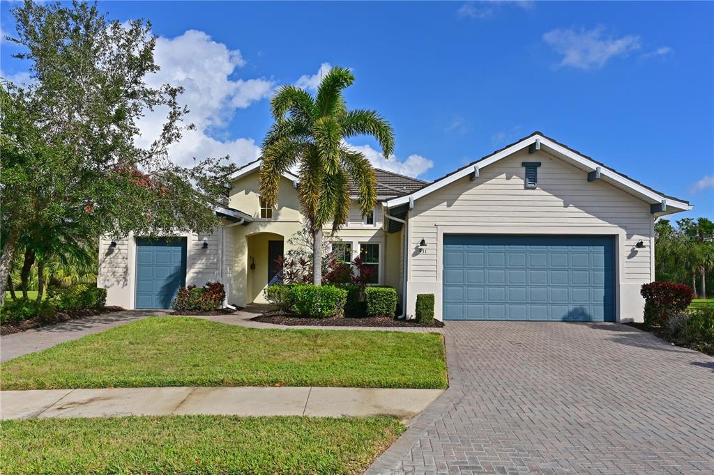 A single-story house with a blue garage door, a palm tree, and a paved driveway — 931 MANGROVE EDGE COURT, BRADENTON, FL