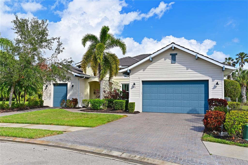 A single-story house with a blue garage door, a palm tree, and a paved driveway — 931 MANGROVE EDGE COURT, BRADENTON, FL