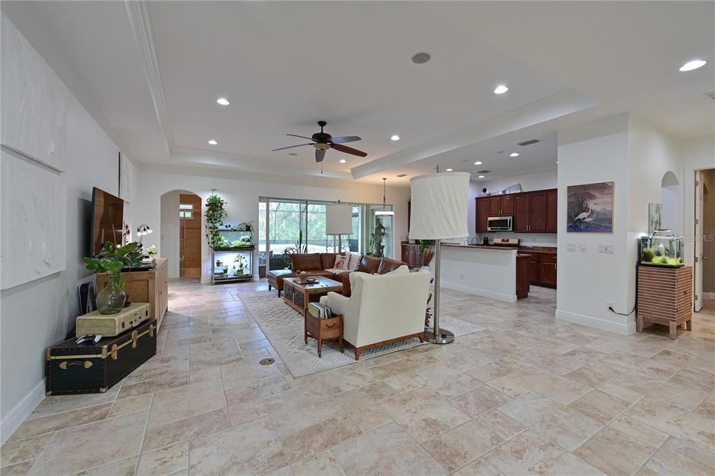An open-concept living room and kitchen feature tile flooring, a tray ceiling, and neutral decor — 931 MANGROVE EDGE COURT, BRADENTON, FL