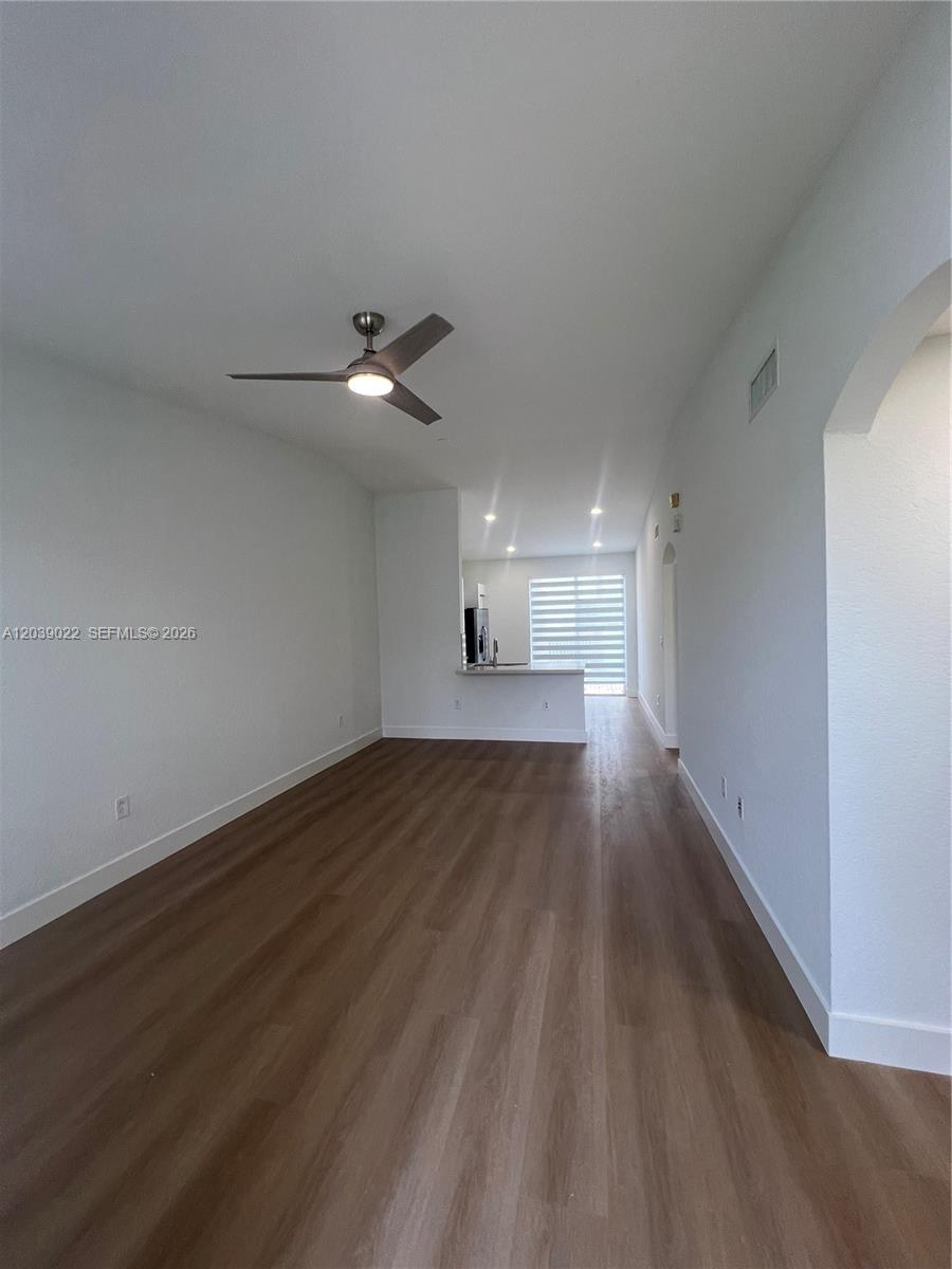 An empty living area features wood-look flooring, white walls, and a ceiling fan — 18739 SW 28th St, Miramar FL 33029, MIRAMAR, FL