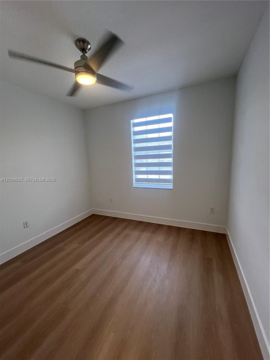 An empty bedroom features light-colored walls, wood-look flooring, a ceiling fan, and a window — 18739 SW 28th St, Miramar FL 33029, MIRAMAR, FL