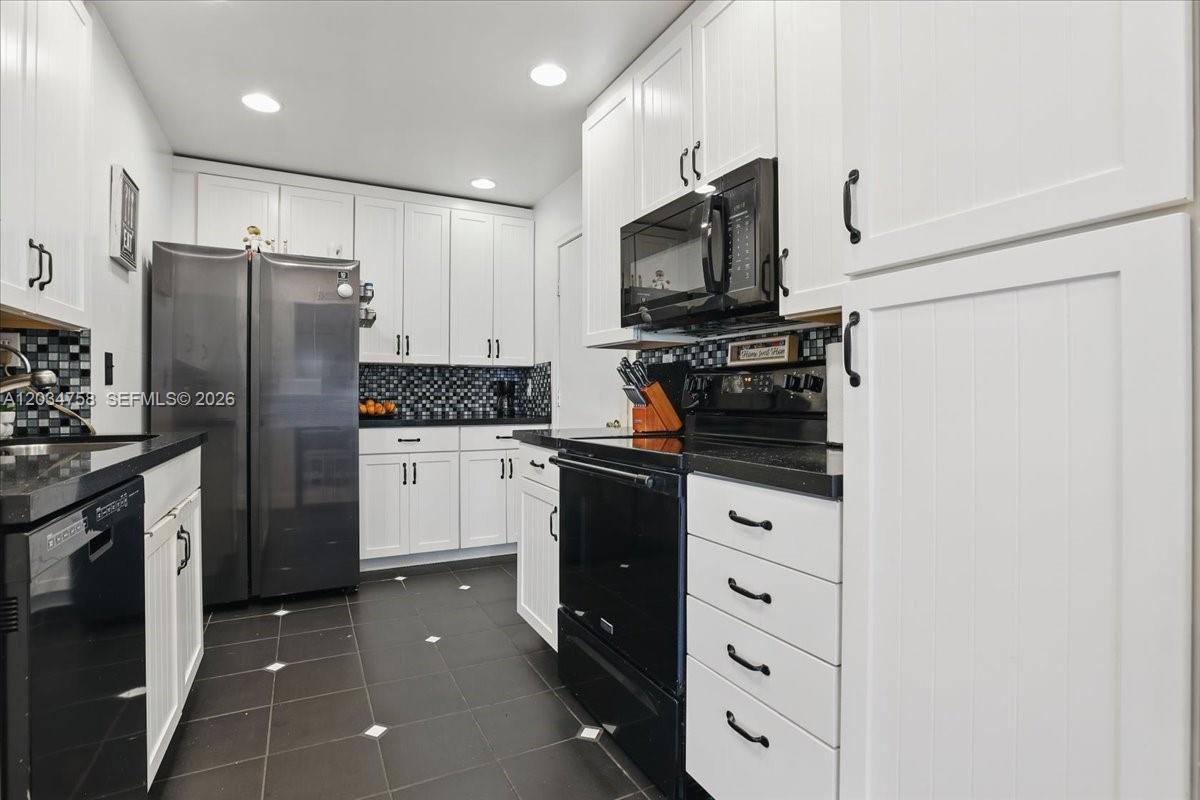 A kitchen features white cabinets, black appliances, dark countertops, and a tiled floor — 5874 SW 97th Ter, Cooper City FL 33328, COOPER CITY, FL