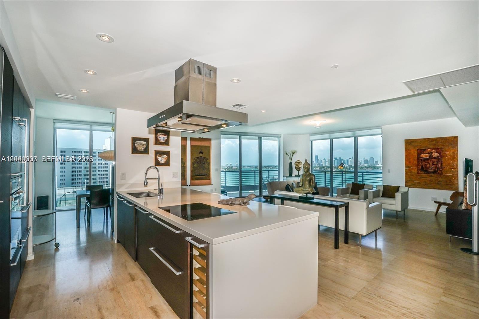 A modern kitchen with a large island overlooks a living area and a waterfront balcony — 1445 16th St # 1103, Miami Beach FL 33139, MIAMI BEACH, FL