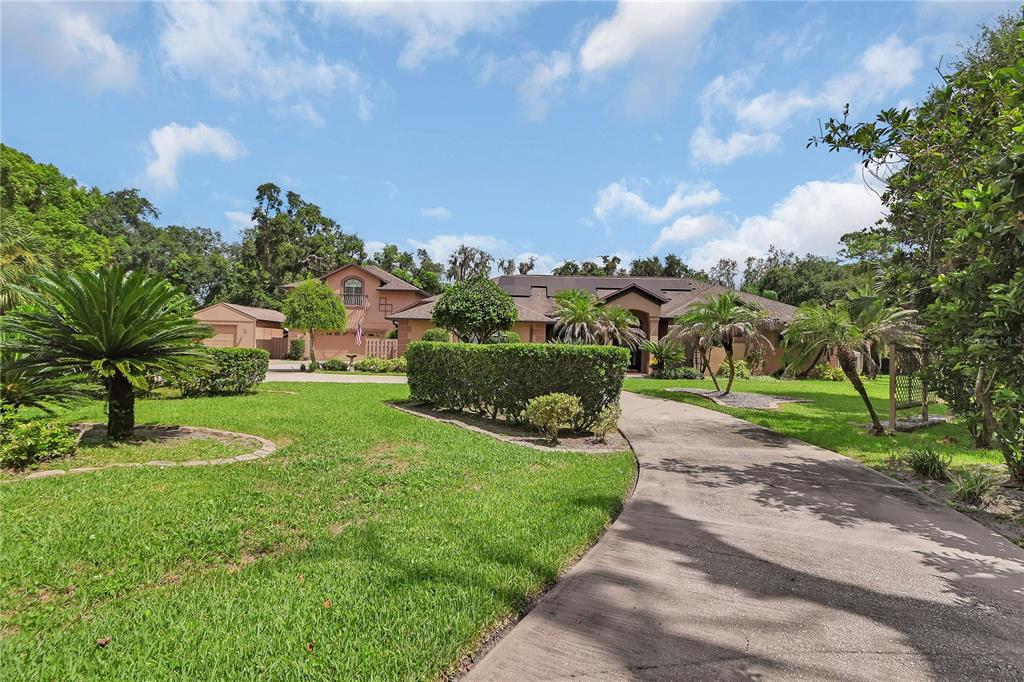 A concrete driveway leads to a large, single-story house with a separate garage and landscaping — 6241 PALOMINO CIRCLE, PORT ORANGE, FL
