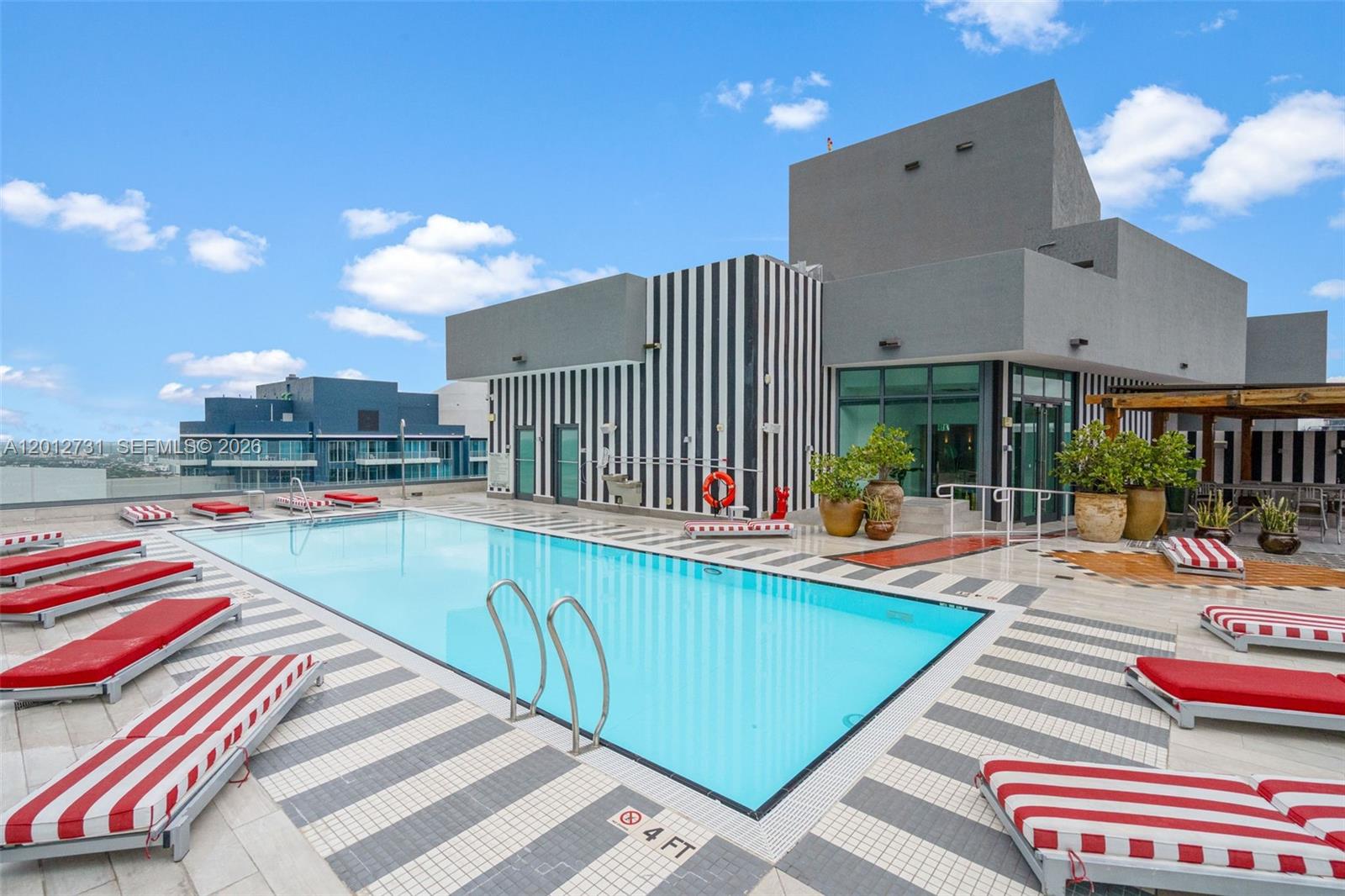 An outdoor swimming pool deck is surrounded by high-rise buildings and potted trees — 1300 S Miami Ave, Miami FL 33130, MIAMI, FL