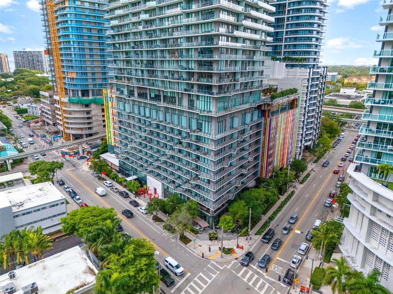 An aerial view shows a modern high-rise apartment building with colorful vertical accents at street level — 1300 S Miami Ave, Miami FL 33130, MIAMI, FL