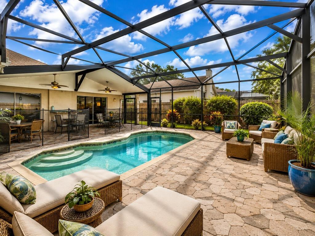 A screened-in patio features a swimming pool, stone pavers, and outdoor lounge furniture — 406 STERLING LAKE DR, OCOEE, FL