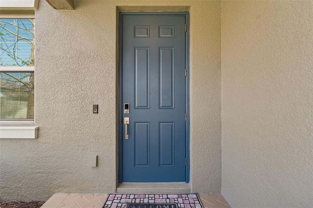 A blue front door with a smart lock is set into a beige stucco wall — 8960 SHADYSIDE LANE, LAND O LAKES, FL