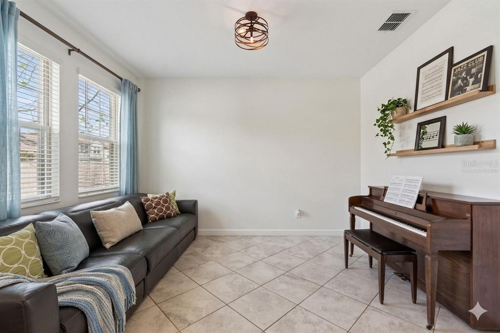 A room with tile floors, a dark leather sofa, and an upright piano against the wall — 8960 SHADYSIDE LANE, LAND O LAKES, FL