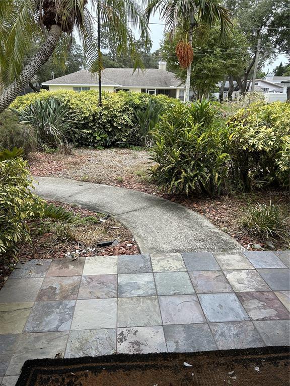 A tiled patio overlooks a curved concrete walkway leading to a house surrounded by landscaping — 1612 GULF BEACH BOULEVARD, TARPON SPRINGS, FL