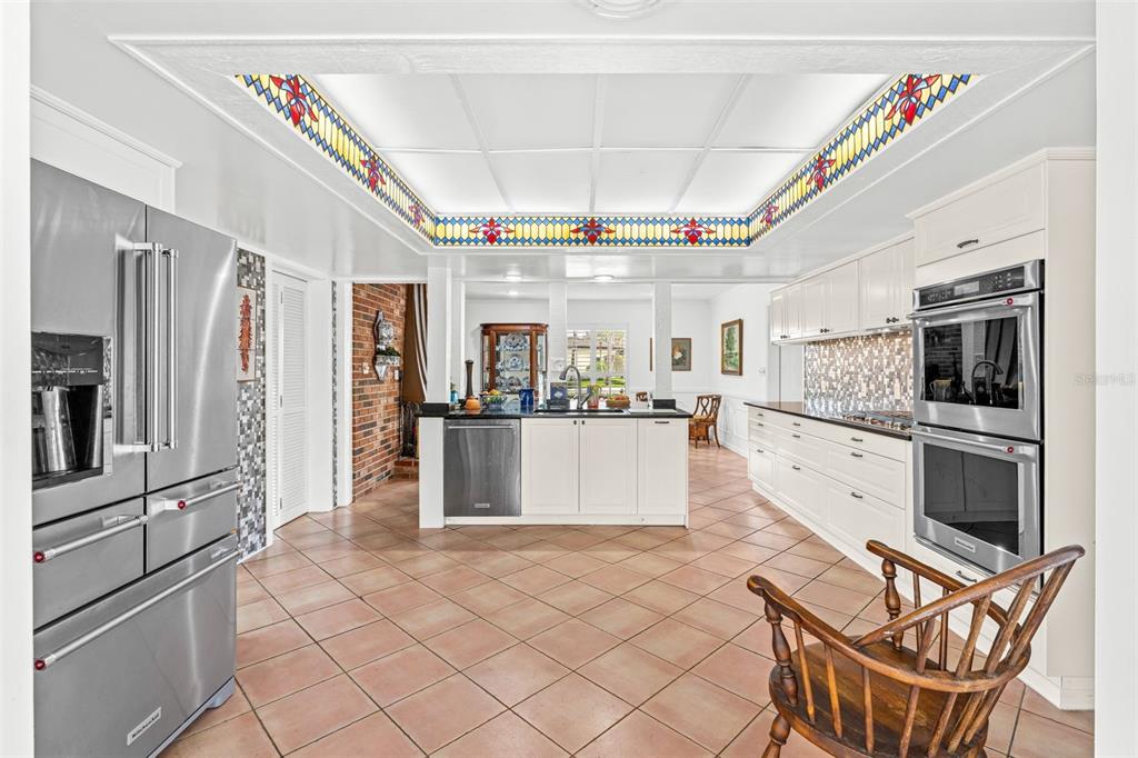 A kitchen with white cabinetry, stainless steel appliances, tile flooring, and a decorative stained-glass ceiling — 1790 BAY SHORE DRIVE, COCOA BEACH, FL