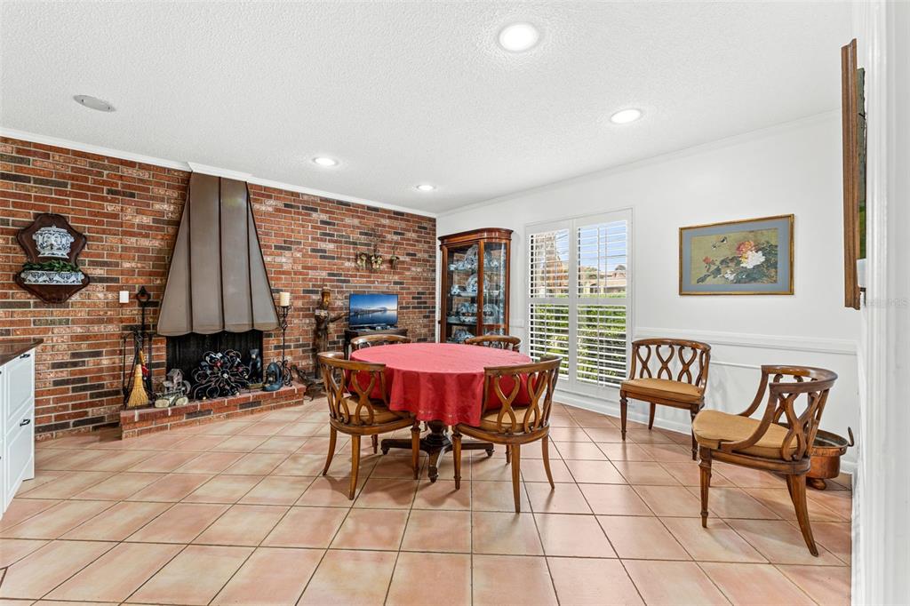 A dining room features a brick fireplace, tile flooring, and a round table with chairs — 1790 BAY SHORE DRIVE, COCOA BEACH, FL