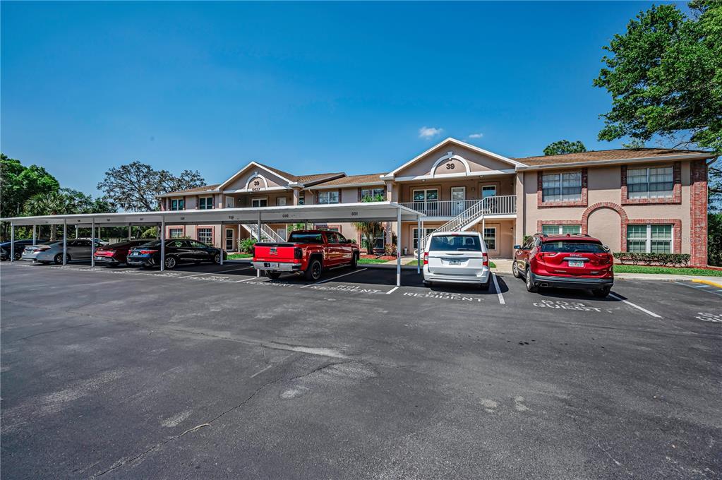A two-story apartment building with a covered parking area and several parked vehicles — 6627 SPRING FLOWER DRIVE UNIT 14, NEW PORT RICHEY, FL