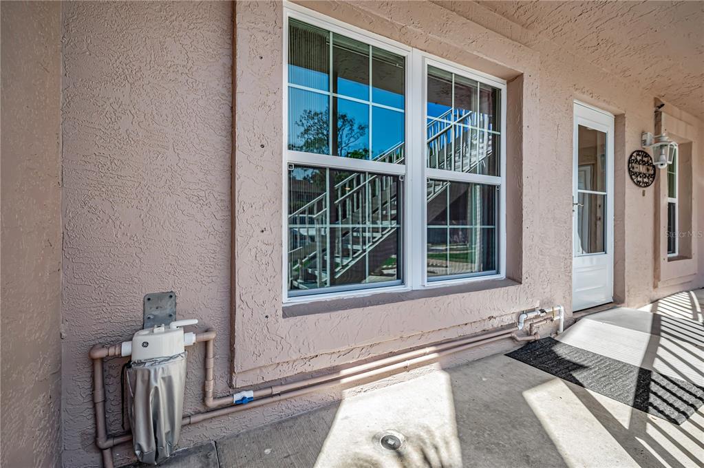 A beige stucco exterior wall features a double-hung window, a white door, and plumbing fixtures — 6627 SPRING FLOWER DRIVE UNIT 14, NEW PORT RICHEY, FL