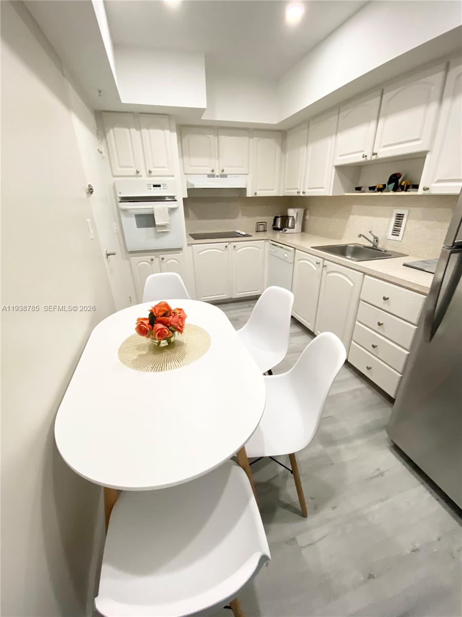 A white kitchen features a dining table, white cabinetry, and light-colored flooring — 4001 S Ocean Dr # 4M, Hollywood FL 33019, HOLLYWOOD, FL