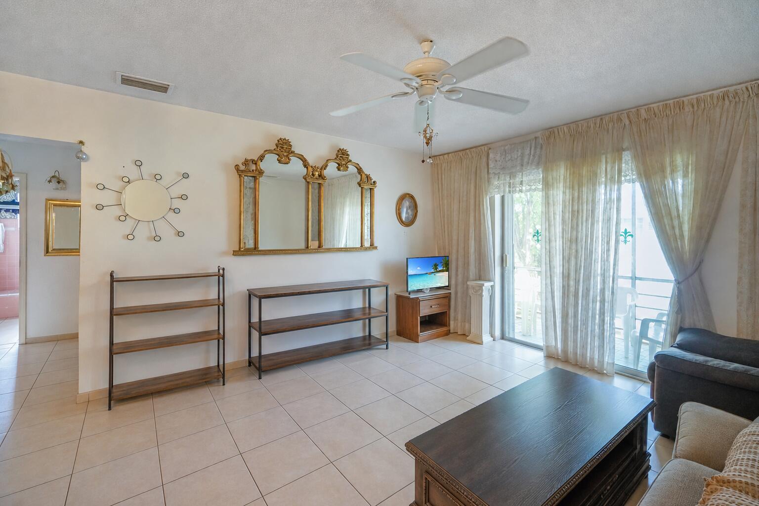 A living room features tile floors, a ceiling fan, a gold-framed mirror, and sliding glass doors — 16750 NE 14th Avenue # 303, Miami FL 33162, MIAMI, FL