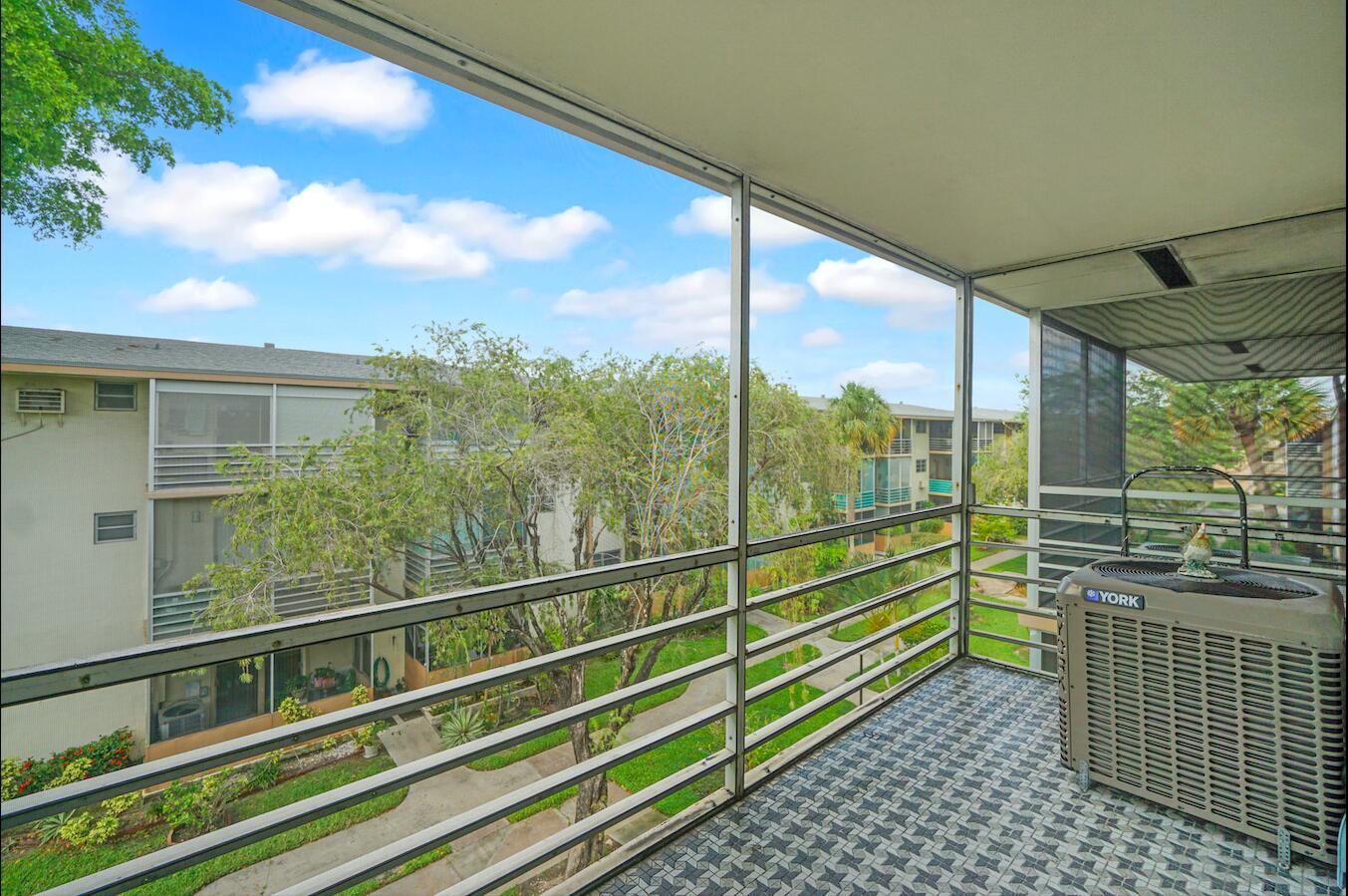 A screened-in balcony features a patterned tiled floor and an outdoor air conditioning unit — 16750 NE 14th Avenue # 303, Miami FL 33162, MIAMI, FL