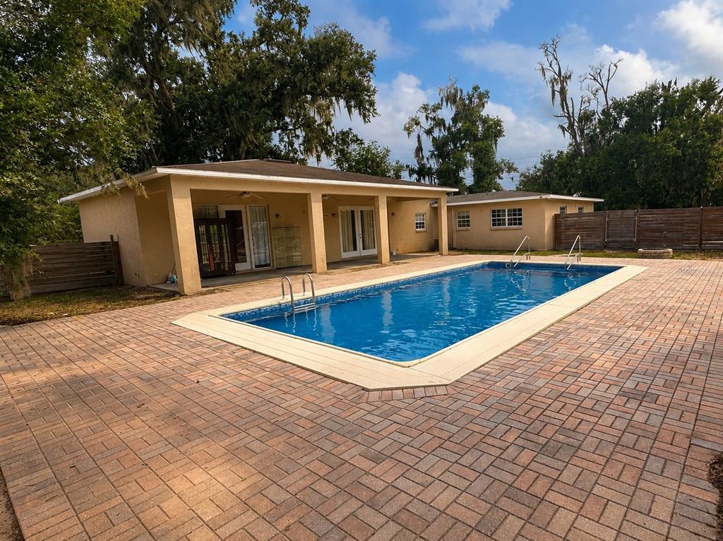 A rectangular swimming pool sits in a paved patio area next to a tan house — 7536 TURKEY CREEK ROAD, PLANT CITY, FL