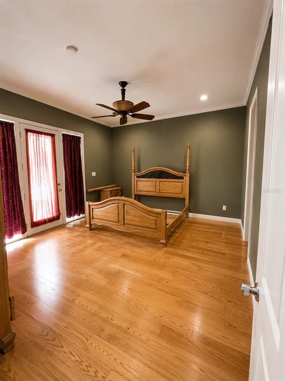 A bedroom features a wooden bed frame, olive green walls, and light-colored hardwood flooring — 7536 TURKEY CREEK ROAD, PLANT CITY, FL