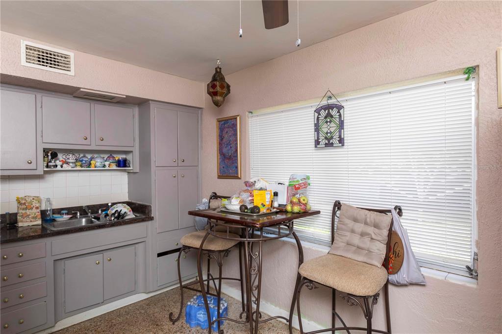 A kitchen features grey cabinets, a small dining table with two stools, and a window — 5344 TANGERINE DRIVE, NEW PORT RICHEY, FL